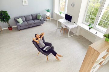 Spacious room with woman taking break from work and relaxing in comfortable armchair