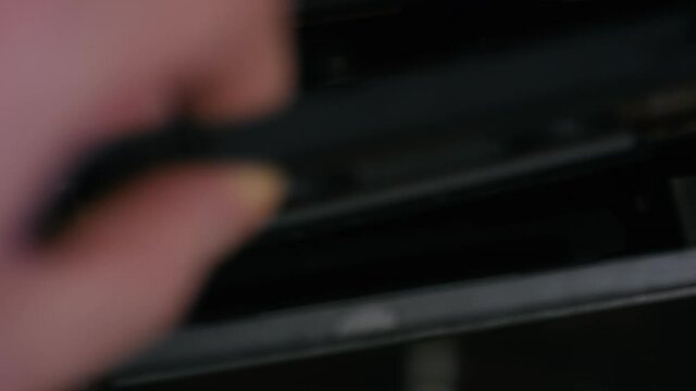 Hand inserts audio cassette and pressing Play button on a vintage stereo tape player recorder. Close-up.