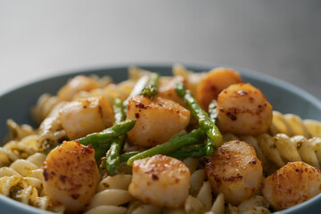 Fusilli pasta with scallops and asparagus in blue bowl closeup