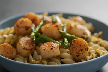 Fusilli pasta with scallops and asparagus in blue bowl closeup