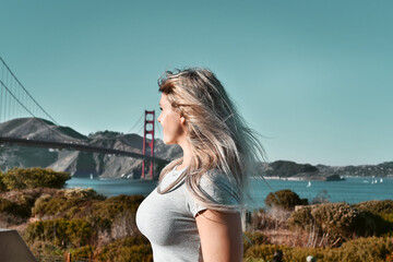 Fototapeta na wymiar Blonde young woman discovering San Francisco and Golden Gate Bridge