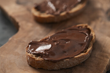 Ciabatta slices with chocolate spread on olive wood board