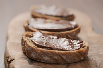 Ciabatta slices with chocolate spread on olive wood board