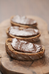 Ciabatta slices with chocolate spread on olive wood board