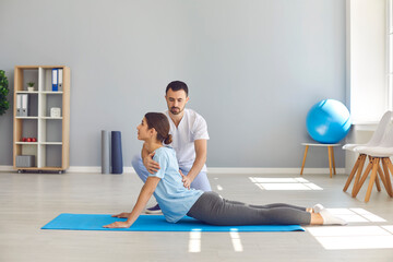 Woman doing exercise to restore back flexibility during physiotherapy after sports injury
