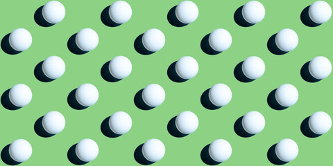 A pattern of white ping pong balls as spheres isolated on uniform green background. Banner size.