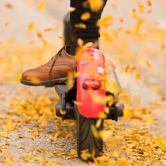 Detail of fashinable hipster girl riding electric scooter in park at fall.