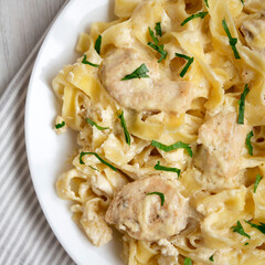 Homemade Chicken Fettuccine Alfredo in a plate on a white wooden table, top view. Flat lay, overhead, from above. Close-up.