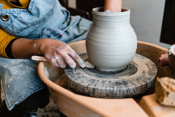Potter making ceramic pot on the pottery wheel with hands