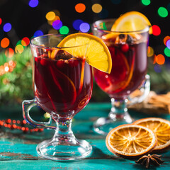 Fragrant, hot punch or mulled wine for Christmas in a glass on a wooden board and branches of a...