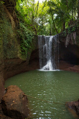 Beautiful waterfall in rainforest. Tropical landscape. Slow shutter speed, motion photography. Foreground with big stone. Nature background. Suwat waterfall, Bali, Indonesia