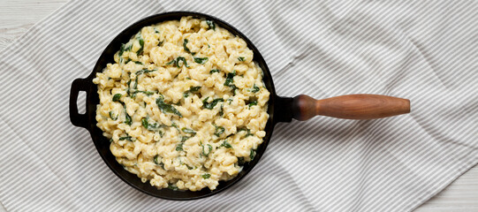 Homemade Spinach Mac and Cheese in a cast-iron pan on cloth, top view. Flat lay, overhead, from...