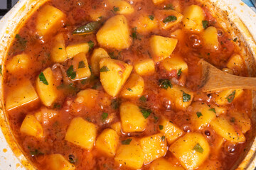 Cooking Greek vegetable stew of potatoes and vegetables in tomato sauce in a large frying pan, top view