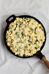 Homemade Spinach Mac and Cheese in a cast-iron pan on cloth, overhead view. Flat lay, top view, from above.