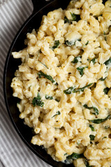 Homemade Spinach Mac and Cheese in a cast-iron pan on cloth, top view. Flat lay, overhead, from above. Close-up.