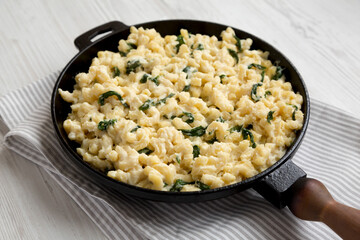 Homemade Spinach Mac and Cheese in a cast-iron pan on cloth, side view. Close-up.