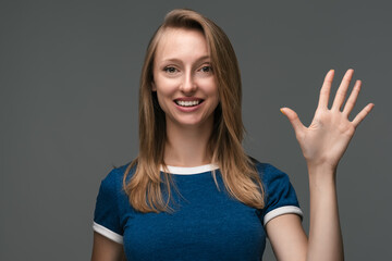 Fototapeta na wymiar Attractive cheerful friendly girl waving raised palm. Human emotions, facial expression concept