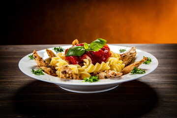 Roast chicken nuggets with fusilli and tomato sauce on wooden table