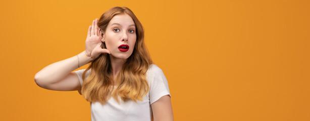 Young pretty woman with wavy redhead holding hand near ear. Copy space