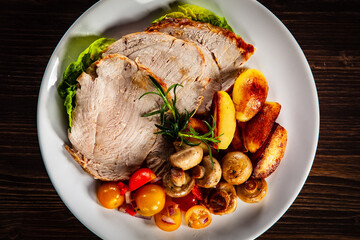 Roasted pork ham, champignons and fried potatoes on wooden table