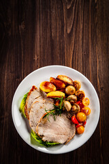 Roasted pork ham, champignons and fried potatoes on wooden table