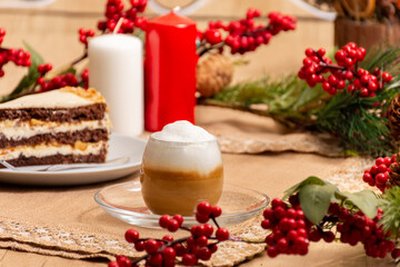 cup of cappuccino with chocolate cream cake on a table decorated for the Christmas holidays. cafe concept