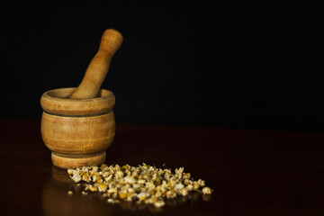 Grinding chamomile in a classic grinder with chamomile flowers