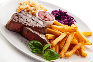 Grilled beef steak with french fries and vegetable salads  served on white background 