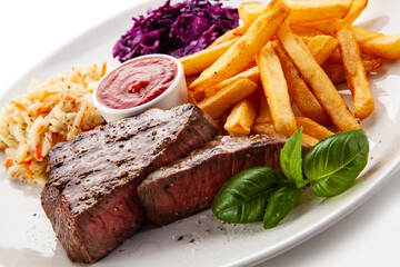 Grilled beef steak with french fries and vegetable salads  served on white background 