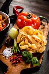 Tagliatelle with pork, tomato sauce, parmesan cheese, basil and vegetables served on wooden table
