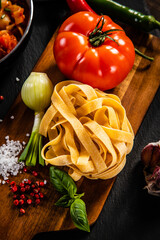 Raw tagliatelle with vegetables served on wooden table
