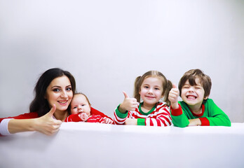 A family in striped pajamas is resting at home. Little children dressed as elves are lying on the sofa. Happy familywith banner.