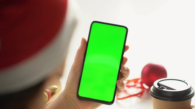 Close-up shot of green screen template smartphone in female hands at home offise. The template can be used to advertise purchases on Christmas Eve. Modent technology and information concept. POV