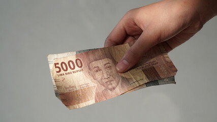 Indonesian rupiah banknotes, 5,000 rupiah, held by girls