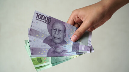 Indonesian rupiah currency, 10,000 rupiah and 20,000 rupiah, is held by women's hands