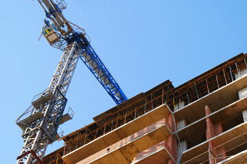 Crane near building. Concrete building under construction.