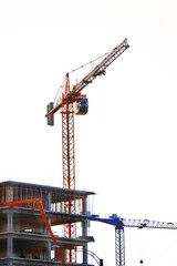 Crane near building. Concrete building under construction. Industrial background.