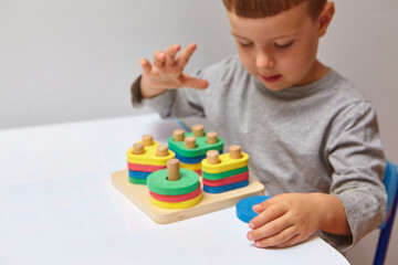 The boy is playing in his room. Learning shapes and colors. A child plays with a sorter. Educational logic toys for kid's. Montessori Games for Child Development.