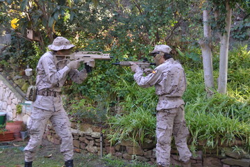 Naklejka premium Dos jovenes apuntandose con fusiles de airsoft