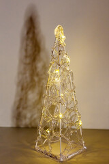 Decorative electric christmas tree from transparent plastic with illumination in golden colors, minimalistic cozy warm holiday mood