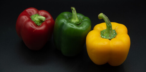 Pimientos colores rojo amarillo y verde sobre fondo negro