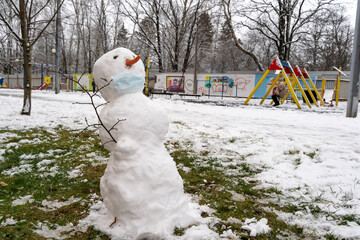 snowman in a protective mask in the snow