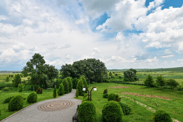 Beautiful spring park scenery with stone pavement, background of blue sky