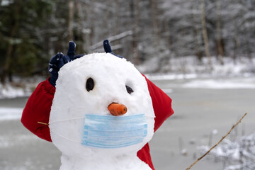 snowman in a protective mask in the snow