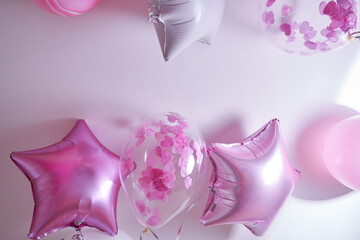 Pink, white and transparent balloons with rose petals inflated with helium on a white background