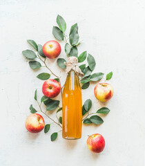 Homemade apple vinegar in glass bottle with apples and green leaves on white background. Top view