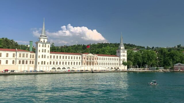 Footage of small fishing boat passing on Bosphorus and historical military school called "Kuleli Askeri Lisesi" in a neighborhood called "Cengelkoy" in Istanbul. It is a beautiful scene.