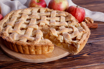 Traditional American Thanks Giving pie with whole organic apples, cinnamon sticks on wooden table. Homemade fruit tart baked to golden crust. Close up, copy space, top view, background.