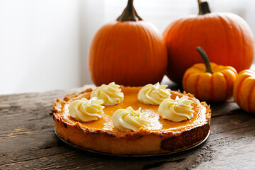 Traditional thanksgiving food on wooden table. Orange delicious homemade pumpkin pie with crust and decorative items. Thanksgiving table setting concept.Top view, close up, copy space, background.