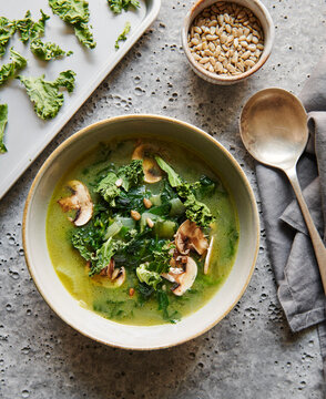 Healthy green soup with kale chips and sunflower seeds.